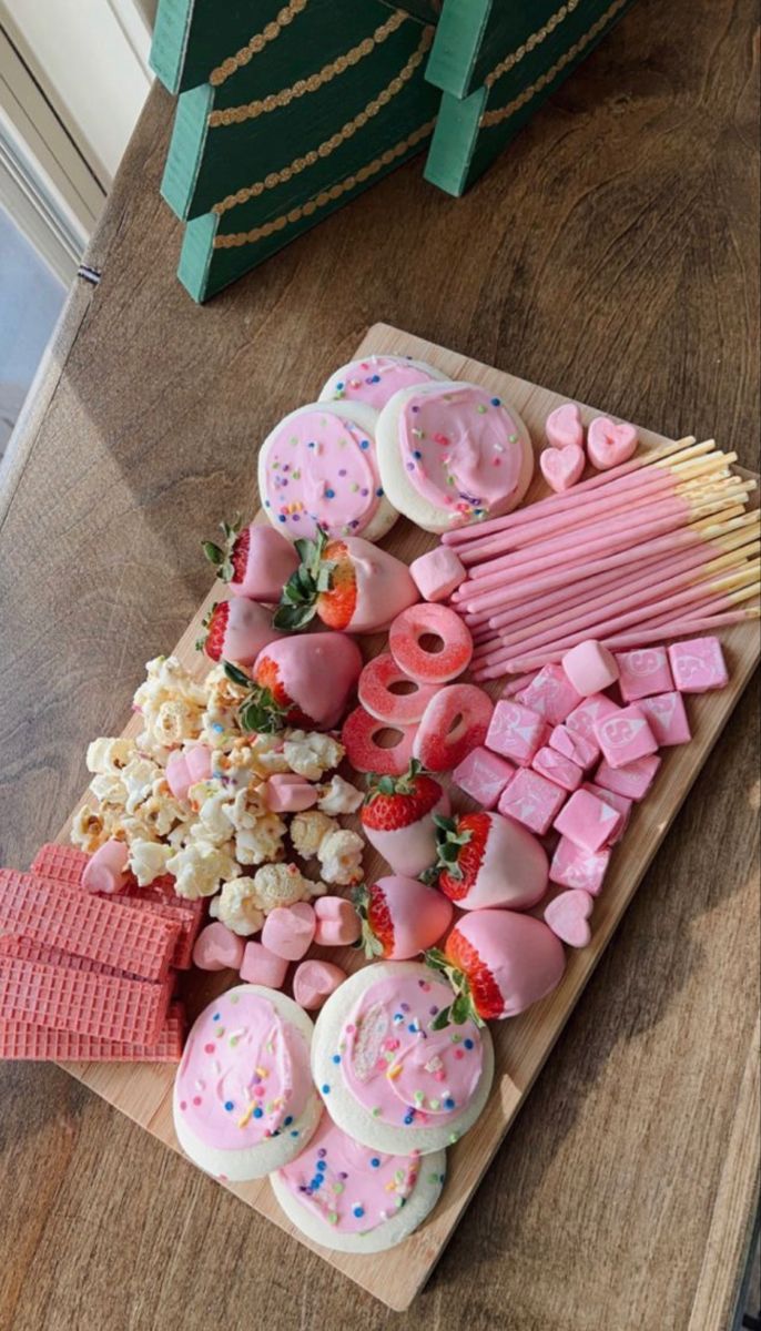 a wooden table topped with lots of pink and white treats