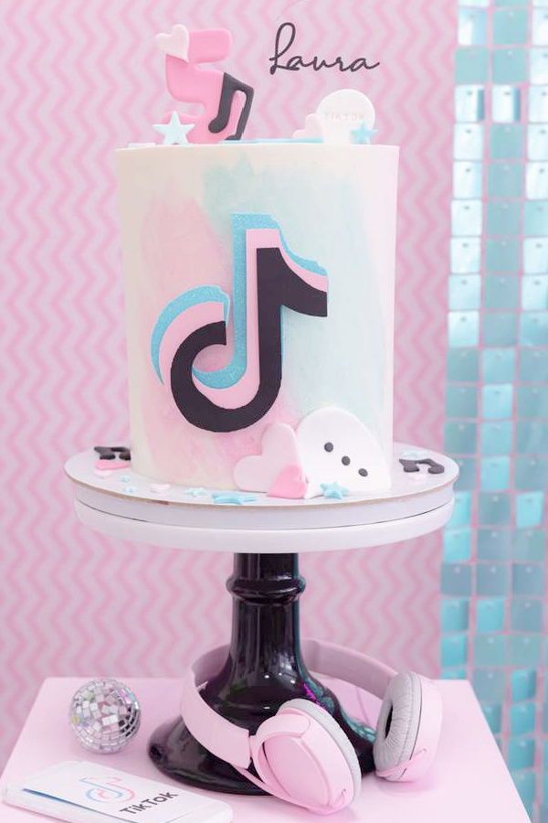 a pink and blue cake with headphones on a white pedestal in front of a pink wall