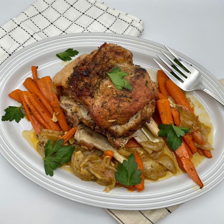 a white plate topped with meat and veggies next to a knife and fork