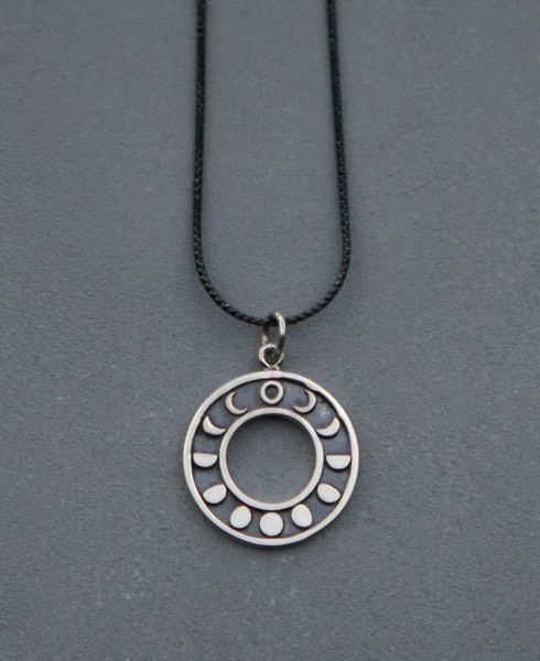 a silver necklace with an open circle design on the front and bottom, hanging from a black chain