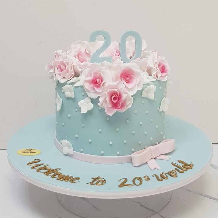 a blue cake with pink flowers and the number 20 on it is sitting on a table