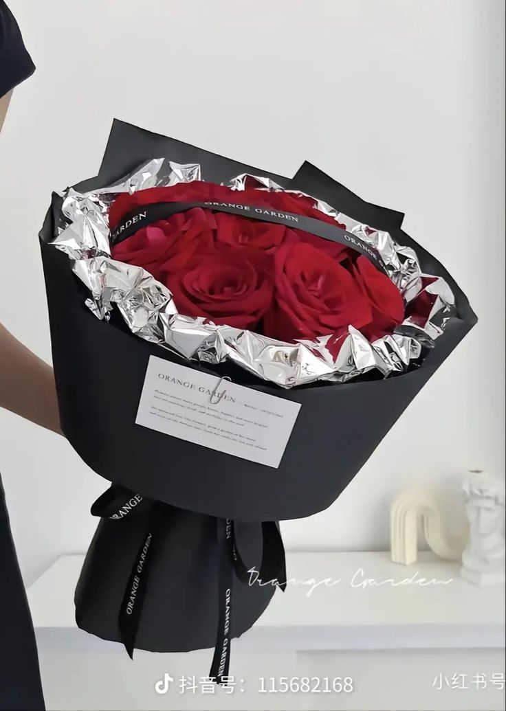 a woman holding a large bouquet of red roses in it's black wrapper