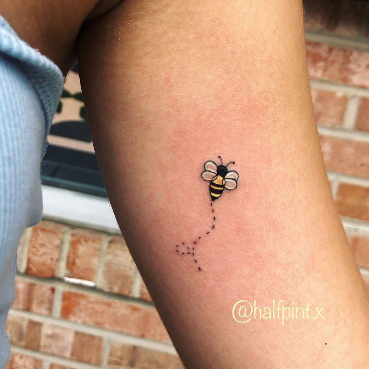 a woman's arm with a small tattoo of a bee on it