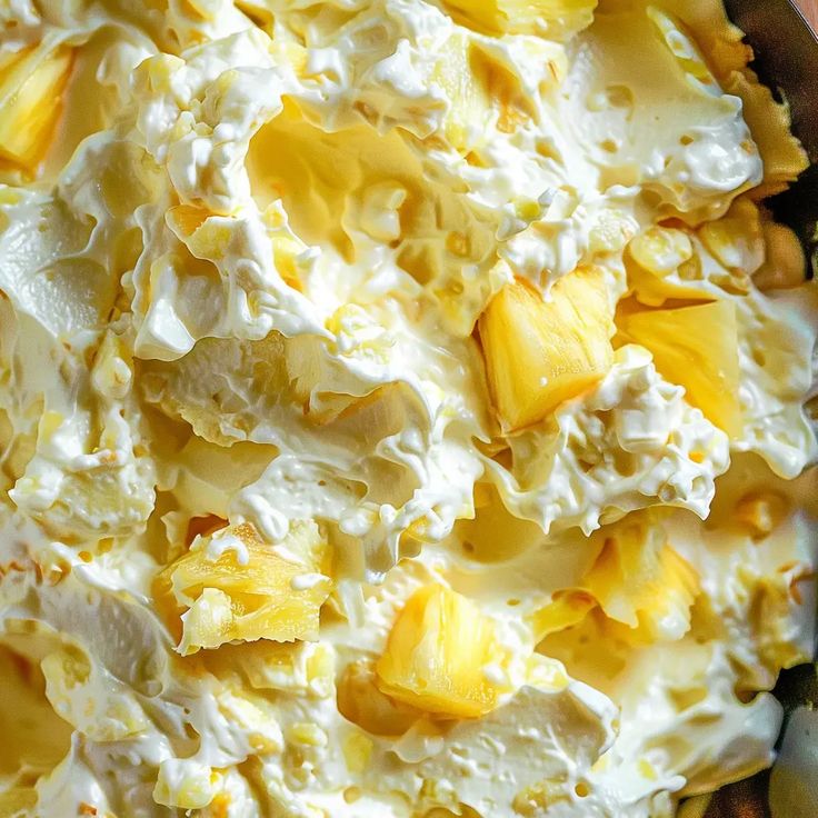 a bowl filled with whipped cream and pineapples on top of a wooden table