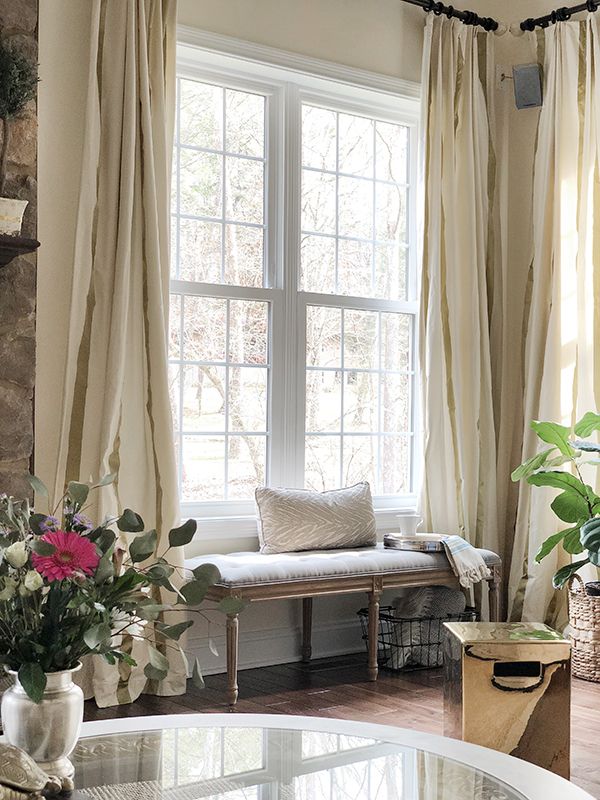 a living room filled with furniture next to a window covered in curtains and drapes