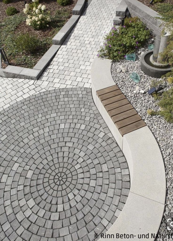 an aerial view of a walkway with benches and flowers in the background, surrounded by rocks