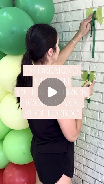 a woman standing next to a wall with balloons