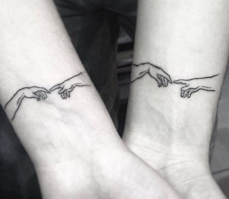 two hands touching each other with tattoos on their wrists