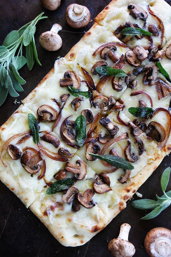 a square pizza with mushrooms on top of it next to some herbs and other ingredients