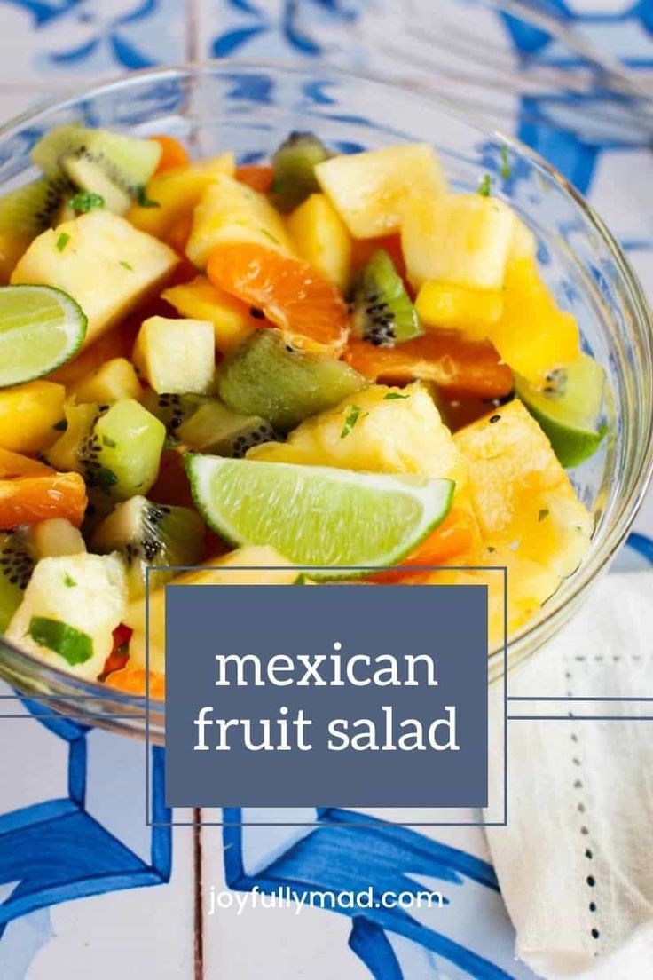 mexican fruit salad in a glass bowl on a blue and white tablecloth with text overlay