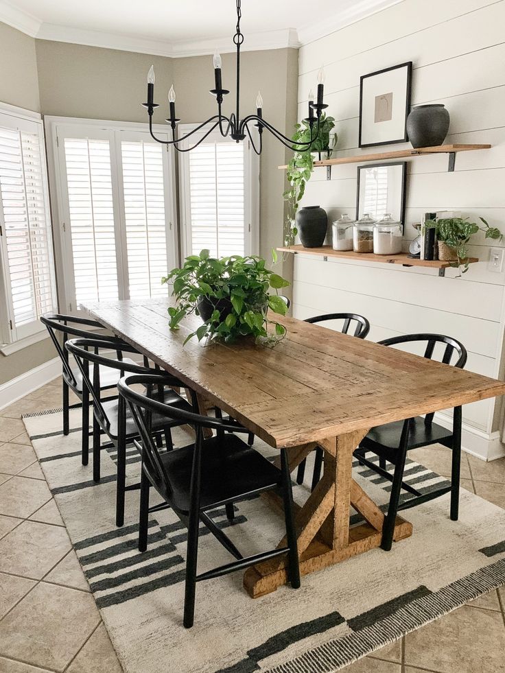 a dining room table with chairs and plants on top of it in front of windows