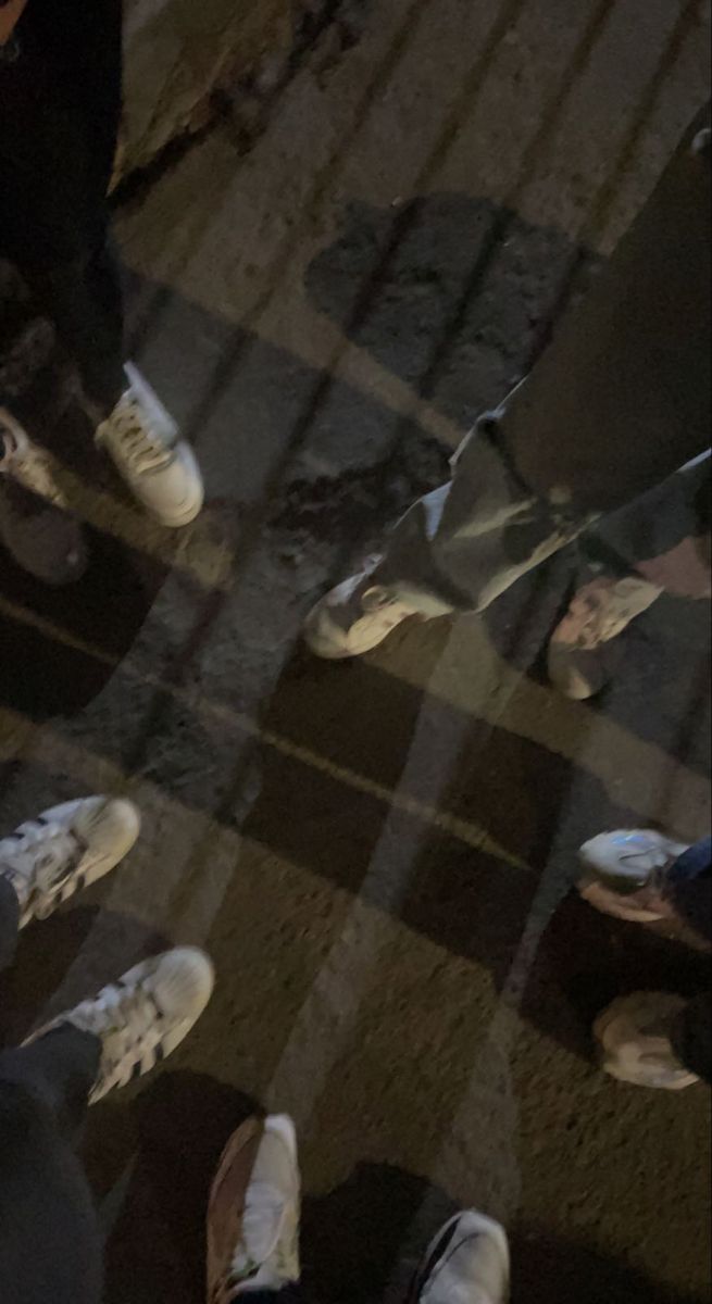 several people standing in a circle with their feet on the ground and one person wearing white shoes