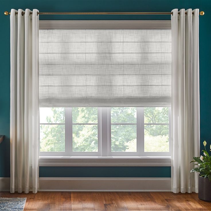 a living room with blue walls and white curtains on the window sill, along with wooden flooring