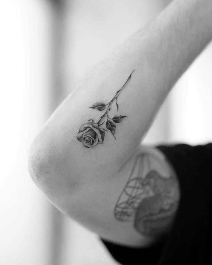 a black and white photo of a woman's arm with a rose tattoo on it