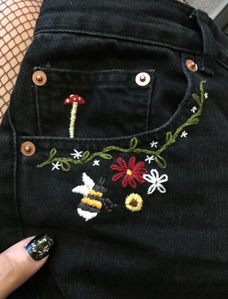 someone is showing off their jeans with embroidered flowers and bees on the side, which are attached to each other