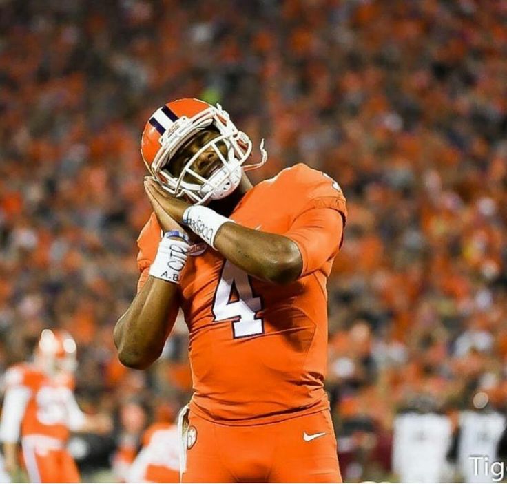 a football player is holding his hands up to his face while standing on the field