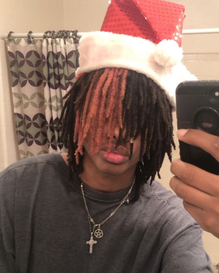 a man with dreadlocks and a santa hat taking a selfie