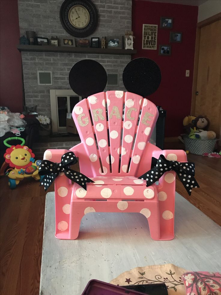 a pink plastic chair with polka dots on it and a black bow around the seat