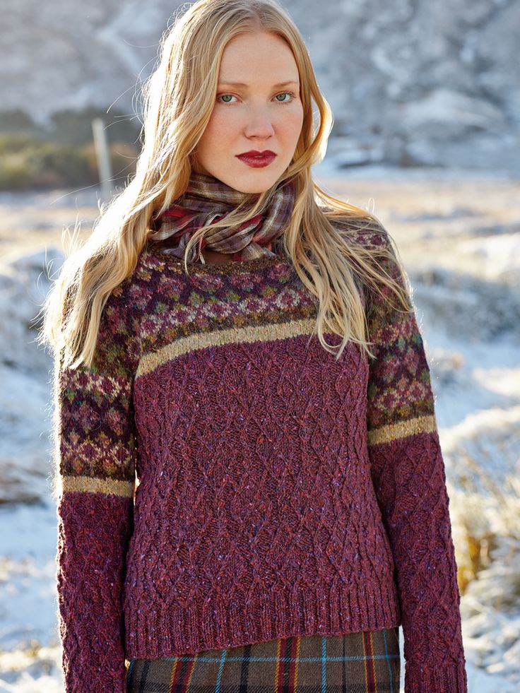 a woman standing in the snow wearing a red sweater and plaid skirt with her hands on her hips