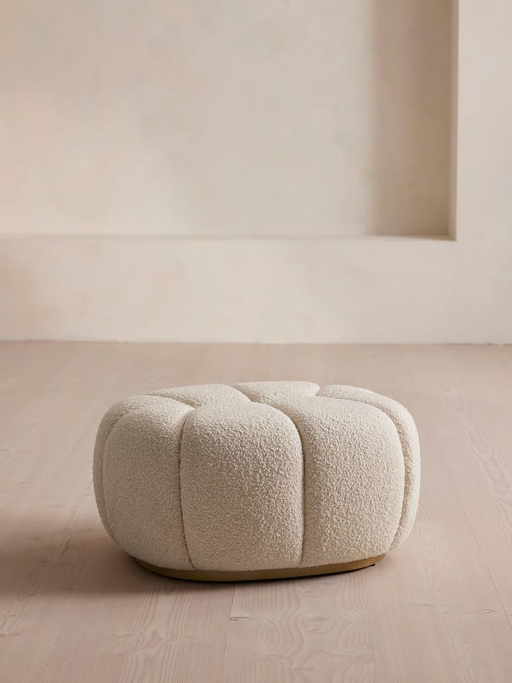 a white poufce sitting on top of a wooden floor next to a window