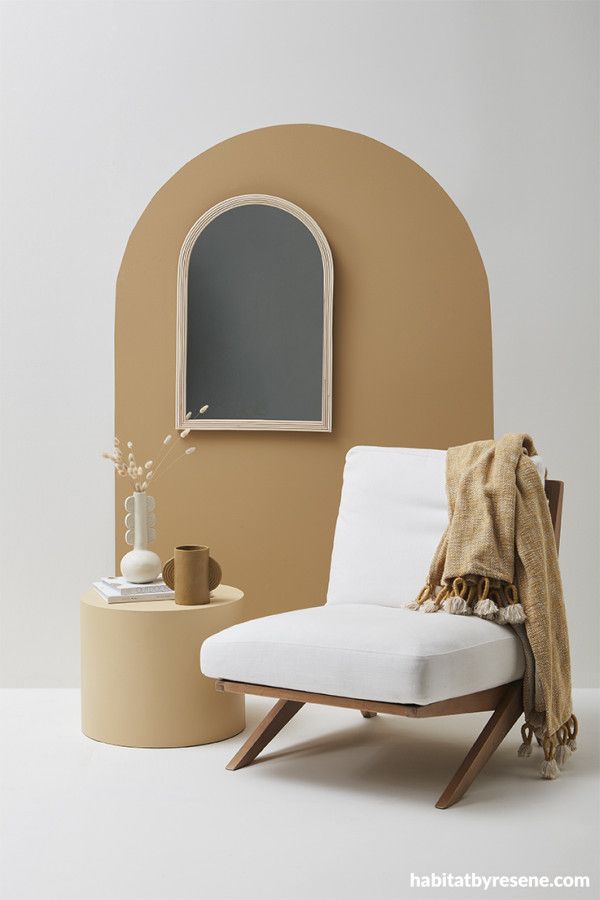 a white chair sitting in front of a mirror next to a table with a vase on it