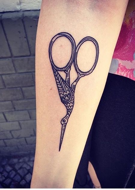 a tattoo on the arm of a woman with scissors in it's middle section