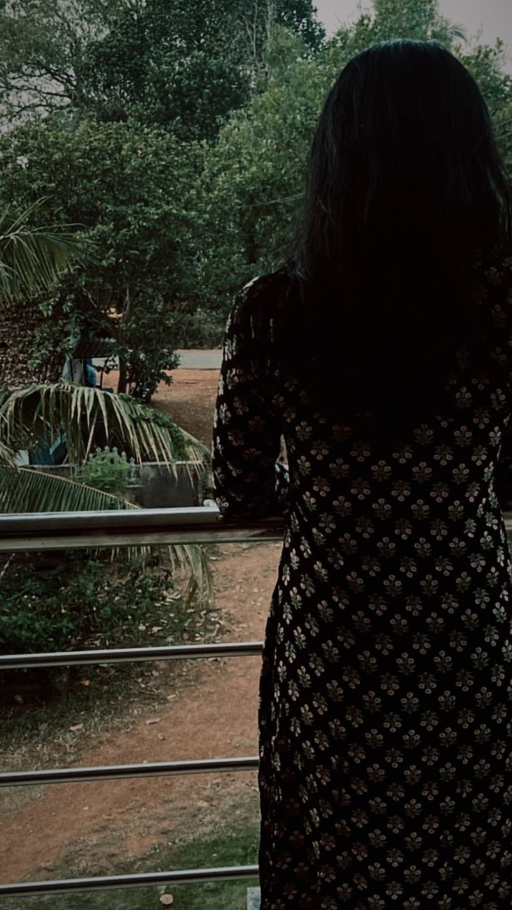 a woman standing in front of a window looking out at trees