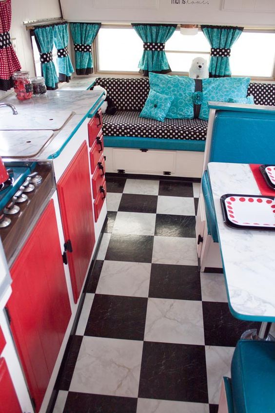 the interior of a camper with checkered flooring and red cabinets, black and white tile