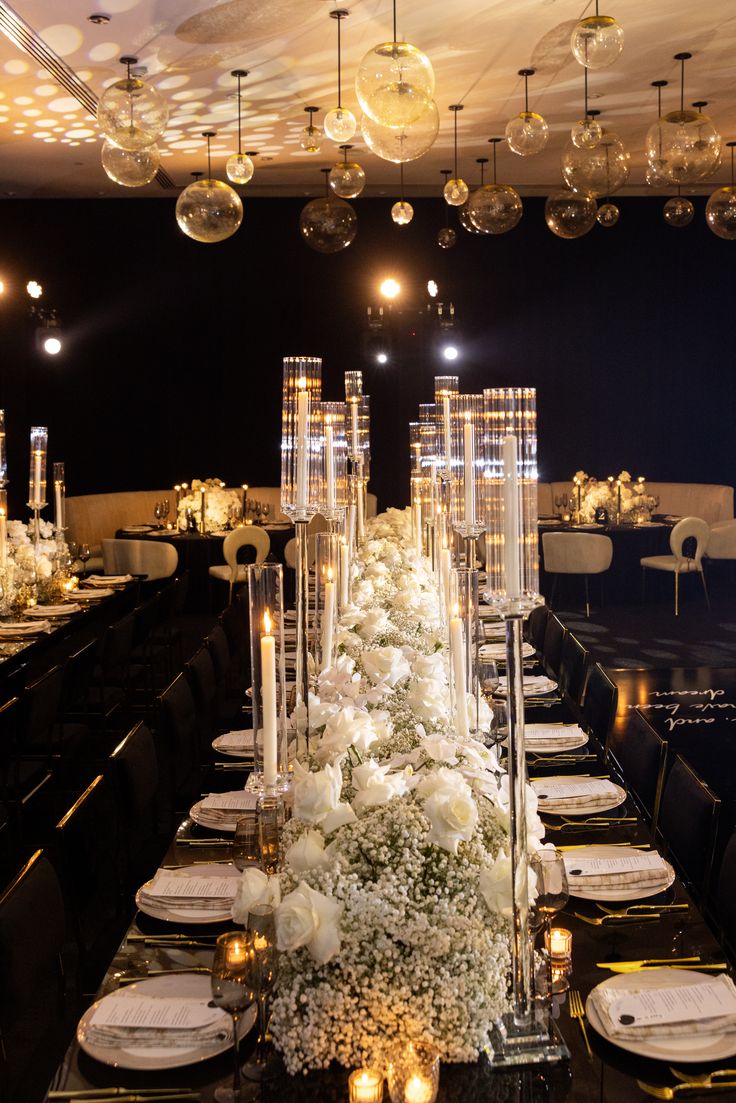 a long table with candles, plates and flowers on it is set for an event