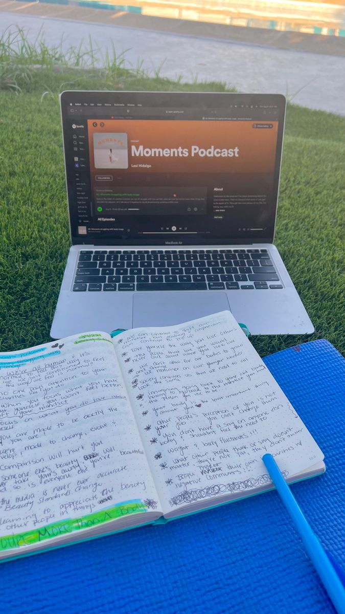 an open notebook sitting on top of a blue mat next to a laptop computer and pen