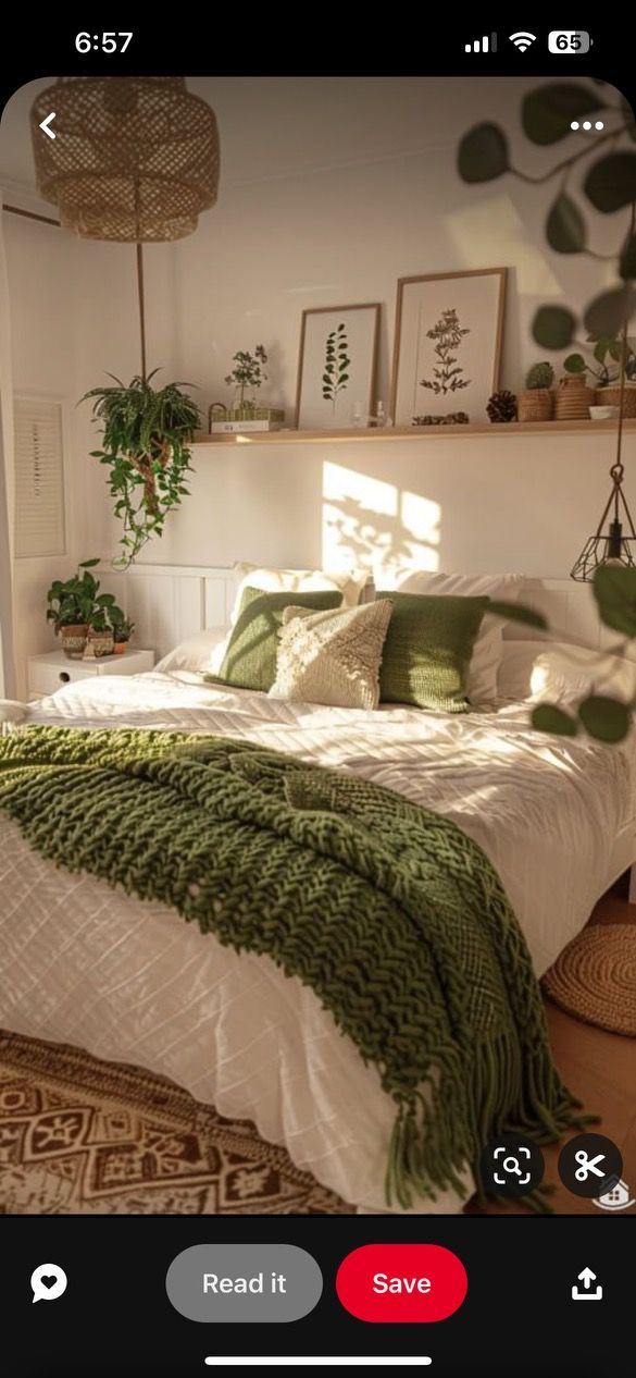 a bed with green blankets and pillows in a bedroom next to a plant on the wall