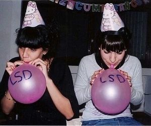 two women sitting on a couch holding balloons with the letters sd and s written on them