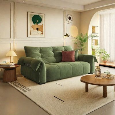 a living room with a green couch and coffee table in front of a window that looks out onto the street