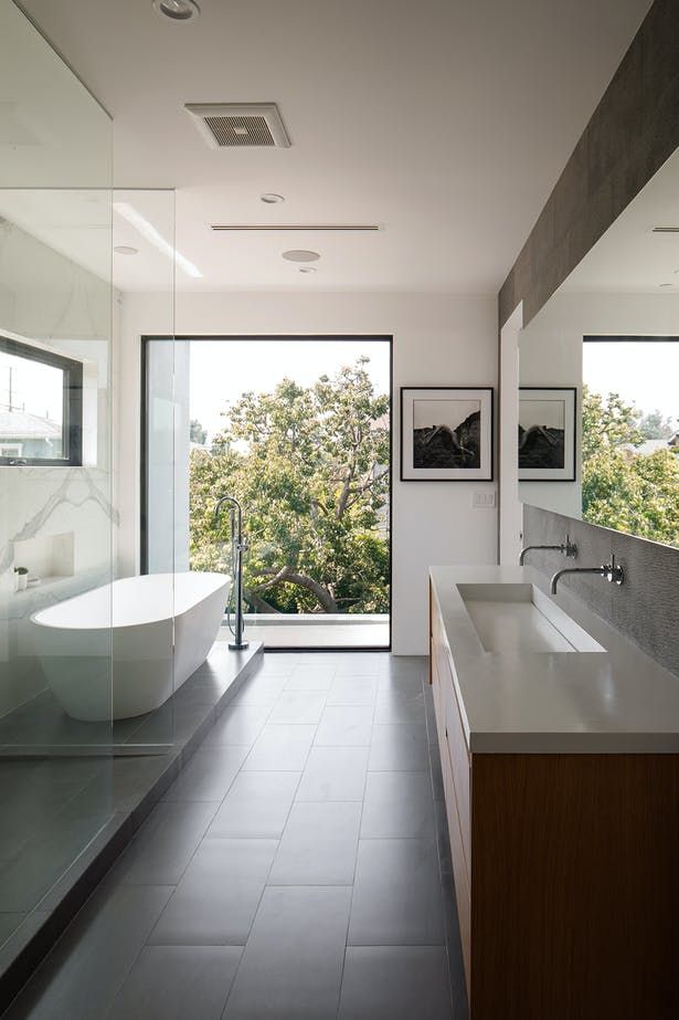 a bathroom with a tub, sink and large glass doors leading to the outside area