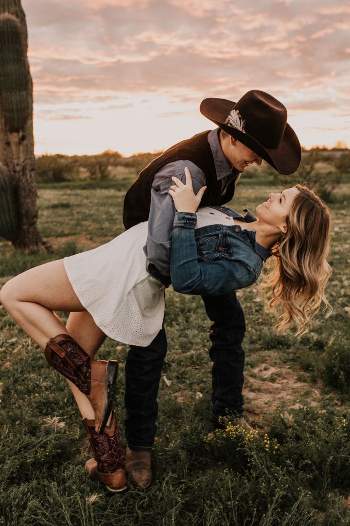 a man and woman in cowboy hats are standing next to each other on the grass