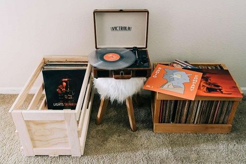 an open record player sitting on top of a wooden table next to other vinyl records