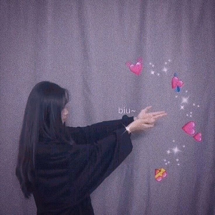 a woman standing in front of a wall with hearts on it