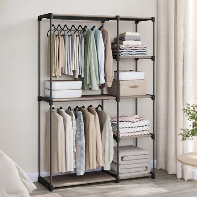 an open closet with clothes hanging on the racks and folded linens in front of it