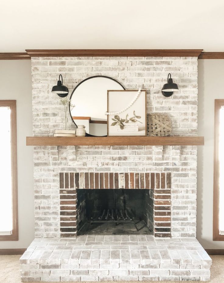 a living room with a fire place and mirror on top of the brick fireplace mantel