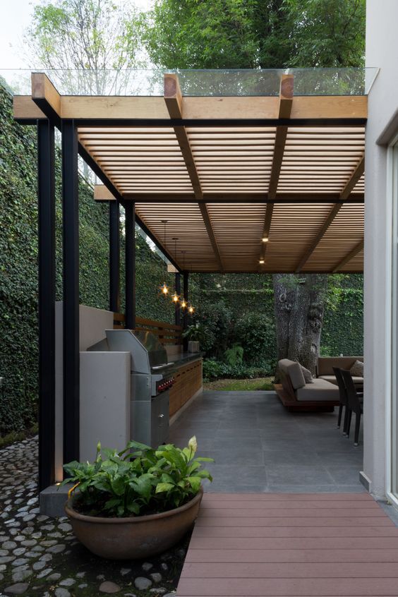 a covered patio with furniture and lights in the evening time, surrounded by greenery