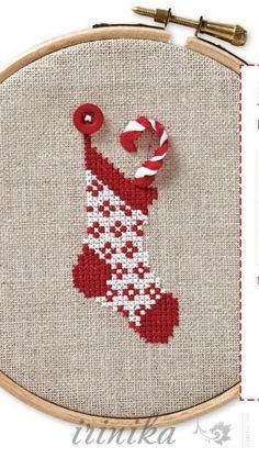 a cross stitch christmas stocking with candy canes hanging from it's side