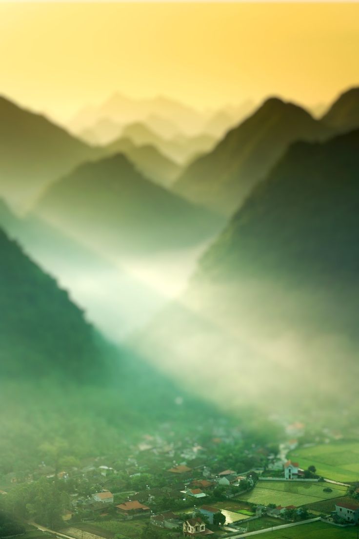 an aerial view of mountains and valleys in the foggy morning light, taken from above