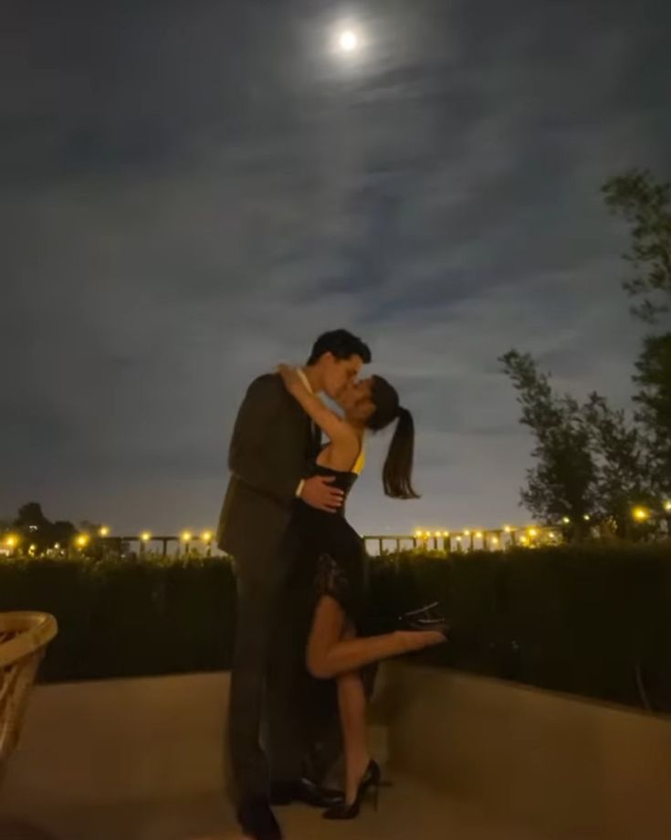 a man and woman are dancing in front of the moon