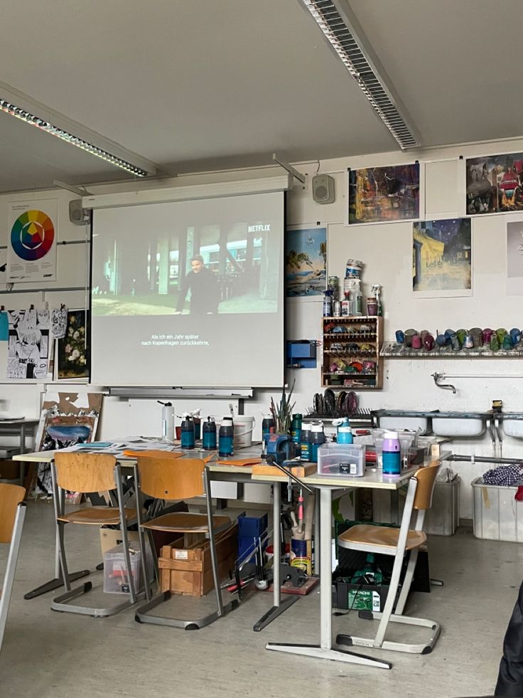 a room filled with desks and chairs in front of a projector screen