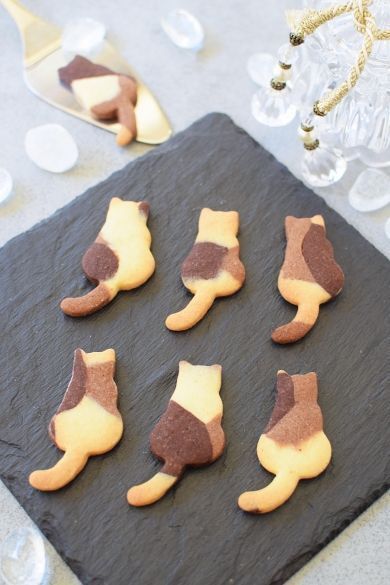 there are many cookies shaped like feet on a slate board next to some wine glasses