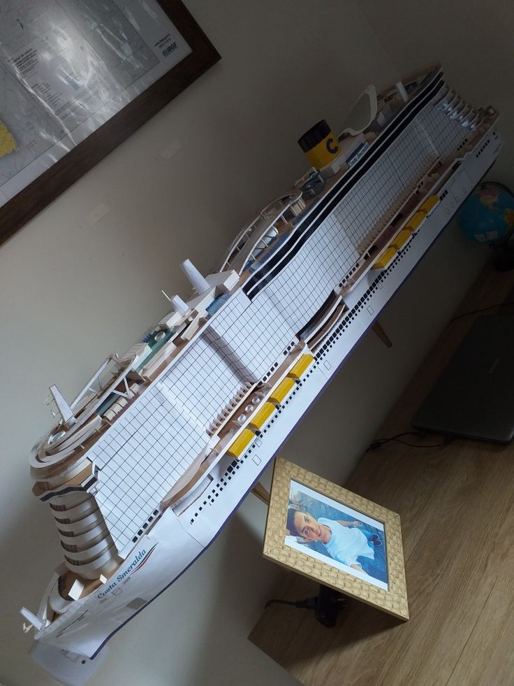 a model of a cruise ship sitting on top of a table next to a framed photo