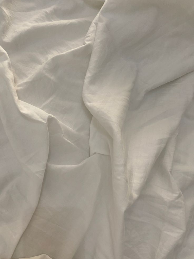 an unmade bed with white sheets and pillows