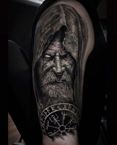 a man's arm with a black and grey tattoo on it, depicting the face of an old man