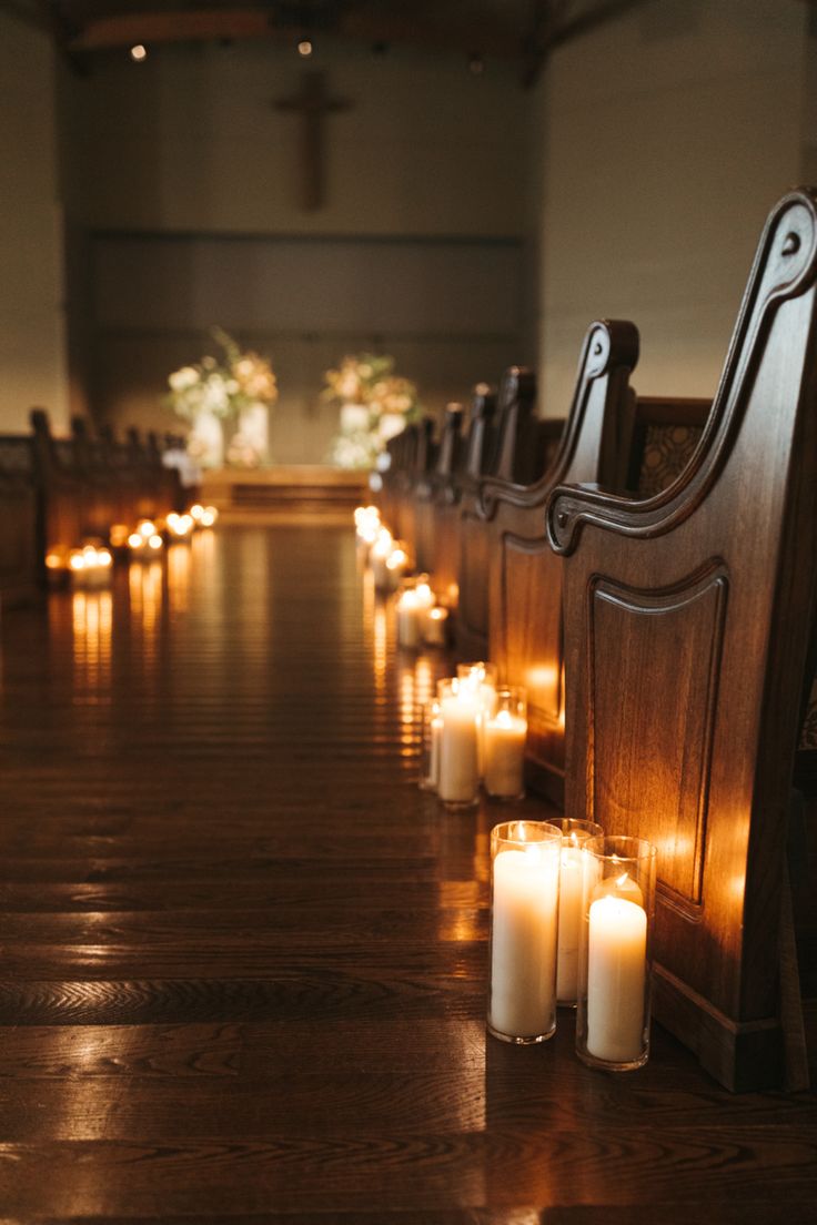 many lit candles are on the ground in front of pews