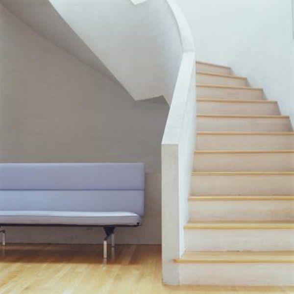 a white couch sitting next to a stair case on top of a hard wood floor